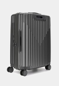 Maleta rígida de color gris oscuro con surcos verticales, asa superior, cerradura de combinación y cuatro ruedas que giran 360 grados.