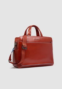 Borsa da lavoro in pelle rossa con una forma elegante, manici corti e tracolla rimovibile. Presenta una tasca frontale e dettagli di cuciture blu.