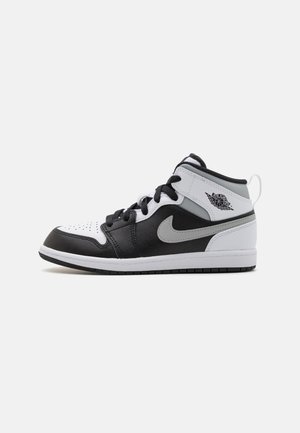 Buty typu mid-top z czarnymi, białymi i szarymi panelami ze skóry, szarym logo Swoosh, czarnymi sznurówkami i logo skrzydeł Air Jordan na kołnierzu przy kostce.
