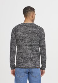 Langarm, ronde hals T-shirt van gestructureerde zwart en grijs gebreide stof. Losse pasvorm met raglanmouwen en een klein logolabel aan de zoom.