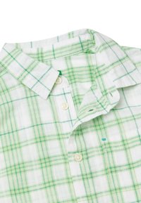 Camicia a maniche corte a quadri in bianco e verde. Presenta un colletto a girocollo e un tessuto morbido e leggero con un motivo a scacchi.