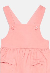 Rosa Babycordkleid mit Schulterträgern, Knopfverschluss, gerafftem Bund und kleinen Schleifen an den Vorderaschen.