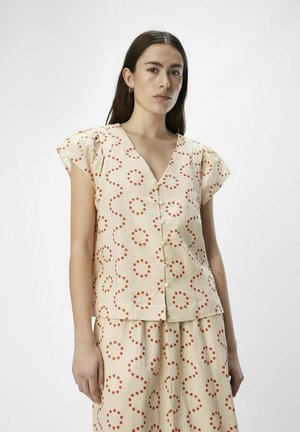 Blusa color crema con mangas cortas y abullonadas, con un patrón de puntos rojos. Diseño de escote en V con cierre de botones en la parte frontal.