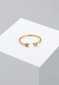 Anillo abierto de oro con dos gemas redondas y transparentes en cada extremo, con un acabado suave y un diseño minimalista.