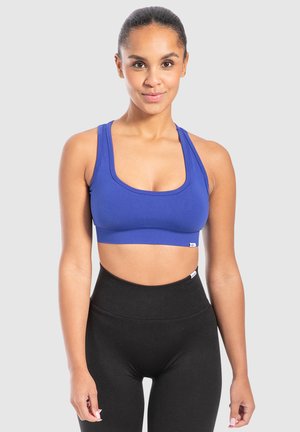Blauwe sportbeha van rekbaar materiaal met een ronde halslijn en brede schouderbanden, gecombineerd met hoge zwarte legging.