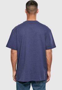 Marineblå oversized t-shirt, ribbet tekstur, korte ærmer og rund halsudskæring. Simpelt design uden synlige logoer eller mønstre.