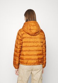 Doudoune orange avec capuche, présentant des sections matelassées horizontales, des poignets élastiques et une taille cintrée. Texture de tissu lisse et brillante.