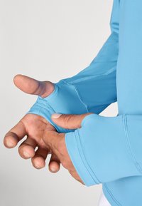 Šviesiai mėlyna ilgos rankovės marškinė su thumbhole detalėmis, pasižyminti lygiu, tampriu audiniu ir sustiprintais siūlių detalėmis papildomam tvirtumui.