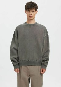 Grauer, gestrickter Pullover mit Rundhalsausschnitt, überschnittenen Schultern und gerippten Bündchen und Saum. Glatte Textur, lockere Passform und minimalistische Designdetails.