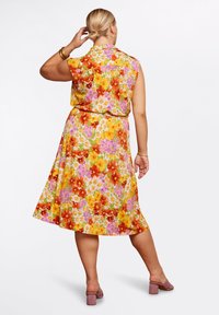 Kortärmad blommig klänning i livfulla färger, med orange, gula och rosa blommor på en grön bakgrund, flaredkjol och knytmidja.