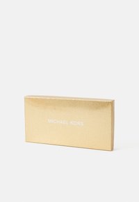 Gold glittered rectangular box with white Michael Kors logo centered on the front against a plain white background.