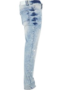 Jeans en denim bleu clair avec une coupe droite. Présente des zones décolorées et des détails de éclaboussures de peinture blanche. Comprend une poche arrière classique.