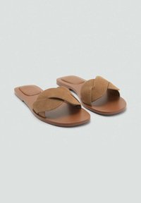 Bruna sandaler med snurrad mockarem och en platt gummisula, med en slät yta och minimalistisk design.