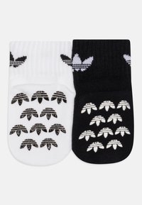Bavlnené ponožky v bielej a čiernej farbe, s kontrastnými logami. Rífľová textúra a jedinečné vzory klasických pruhov a emblémových akcentov.
