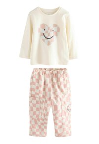 T-shirt à manches longues crème avec graphique en forme de cœur ; pantalon à carreaux rose et blanc avec poches et motif sourire. Tissu en coton, coupe décontractée.