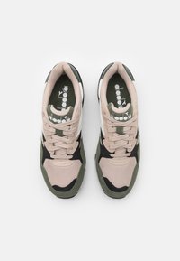 Par de zapatillas Diadora en beige, verde, negro y blanco con cordones y plantillas de marca, vistas desde arriba sobre un fondo blanco.