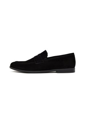 Mocasines de ante negro con un acabado suave, puntera redondeada, detalle decorativo de tira y suela plana de goma. Diseño sencillo y aerodinámico.
