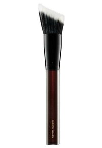 Pennello per trucco con una testa piatta e inclinata, dotato di setole nere e un manico lucido di un rosso scuro con testo dorato che recita "Kevyn Aucoin."