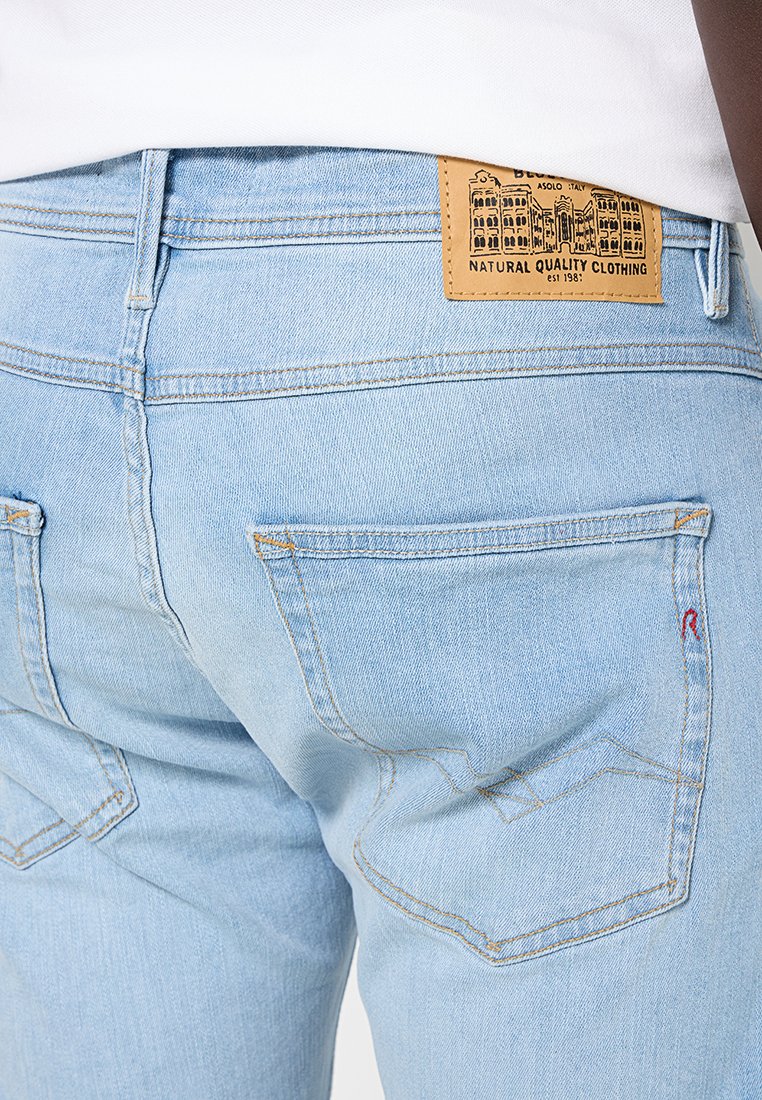 Lichtblauwe denim jeans met een soepele textuur, voorzien van achterzakken, oranje stiksels en een bruine leren label met details op de tailleband.