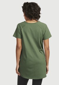 Grøn bluse med korte ærmer lavet af blødt stof, har raglan-ærmer, rund kant og en afslappet pasform for komfort.