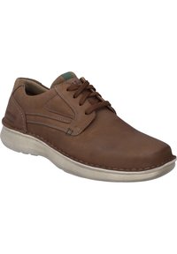 Bruine leren schoen met een ronde neus, vetersluiting, beige loopzool en groene accent bij de hak, met contrasterende stiksels.