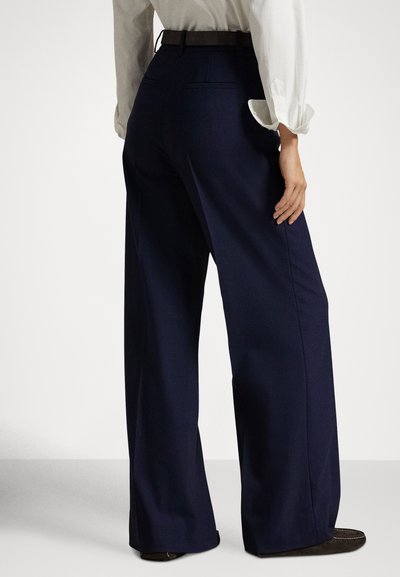 Calças largas azul-marinho com textura suave, apresentando cintura alta, passadores para cinto e dois bolsos traseiros. O tecido é concebido para o conforto.