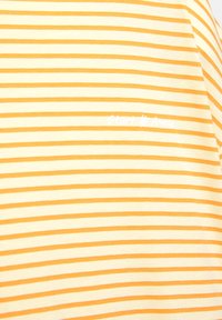 T-shirt rayé jaune et blanc en coton, arborant un logo « Start Anew » en blanc sur la partie gauche de la poitrine.