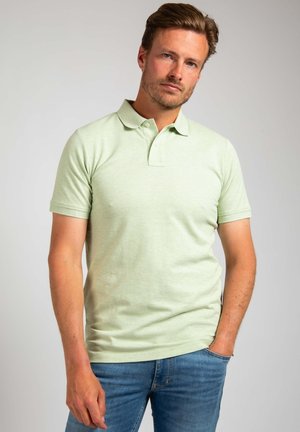 Lichtgroene polo met korte mouwen en een klassieke kraag, gemaakt van zachte stof, gecombineerd met blauwe denim jeans. Minimalistisch ontwerp.