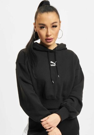 Sudadera recortada negra hecha de algodón. Presenta una capucha con cordón, puños acanalados y un logotipo blanco de Puma en el pecho. Textura suave.