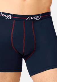 Dunkelblaue Boxershorts mit figurnahem Design, aus weichem Material, mit kontrastierendem roten Stich und einem markierten Gummibund.