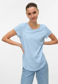 Lichtblauwe blouse met korte mouwen en een ronde halslijn, voorzien van kleine donkerblauwe hartvormige patronen en een gladde, zachte textuur.