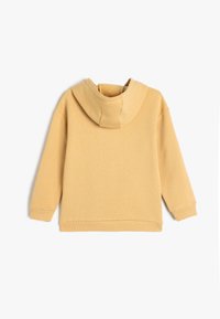 Sudadera amarilla con dobladillo y puños acanalados, con una capucha grande y redondeada y una tela suave y texturada. Diseño simple sin detalles adicionales.