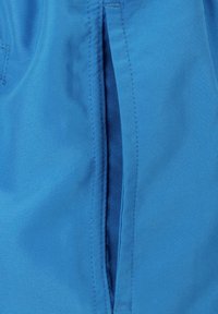 Blauwe stof met een gladde textuur, voorzien van een verticale ritssluiting en nette stiksels langs de randen. Geen extra patronen of accenten.