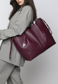 Bordeaux leren tote bag met een textuurafwerking, voorzien van een zilveren letter "P" bedel en verstelbare banden. Groot en ruim ontwerp.