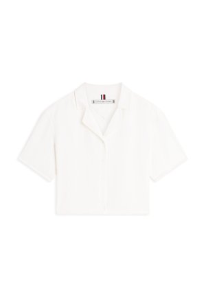 Biały krótki rękaw krótka koszulka z wyciętym kołnierzem i widoczną metką Tommy Hilfiger wewnątrz dekoltu.