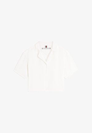 Biały krótki rękaw krótka koszulka z wyciętym kołnierzem i widoczną metką Tommy Hilfiger wewnątrz dekoltu.