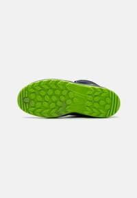 Schoen met een donkere bovenkant en een groene rubberen loopzool met een gestructureerd profiel voor grip. Geschikt voor buitenactiviteiten.