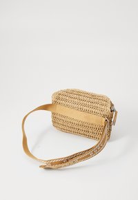 Woven straw bag in natural beige, rectangular shape with a flat bottom. Features a tan fabric strap with white logo accents.