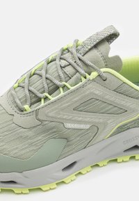 Baskets de sport gris clair avec une tige texturée, des accents réfléchissants et des lacets vert fluo. Présente une semelle rembourrée et une doublure respirante.