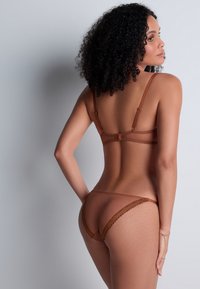 Soutien-gorge sans fil marron et string assorti, présentant un tissu transparent, un délicat bord en dentelle et des bretelles réglables, mettant en valeur un design minimaliste.
