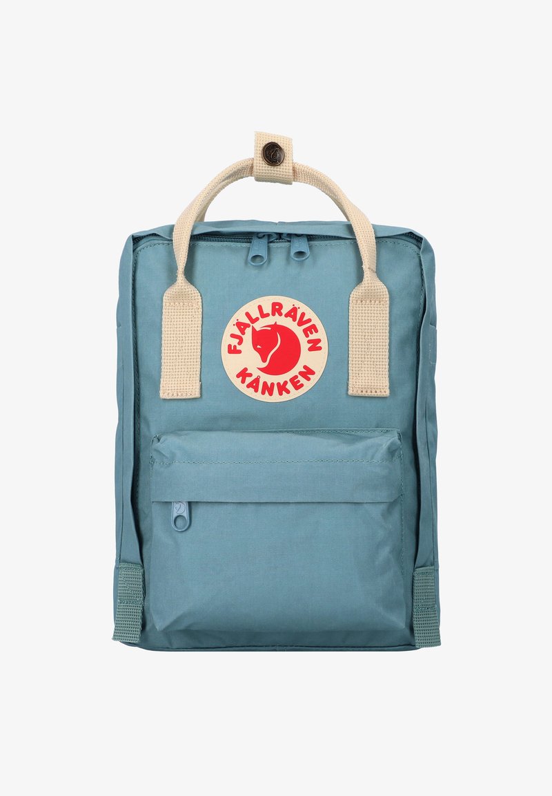 Sac à dos bleu clair de forme rectangulaire, avec une poche avant zippée, des bretelles beige tissées et un écusson logo circulaire.