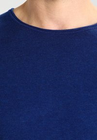 Mörkblå kortärmad skjorta med en slät yta och en bred, rund halsringning. Tyget verkar mjukt och något stretchigt.