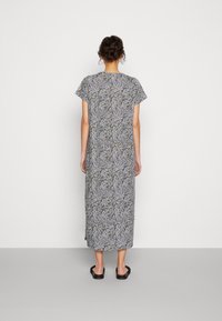 Vestido maxi com padrão de folhas em preto e branco, mangas curtas, ajuste solto, tecido leve, silhueta reta com comprimento até o tornozelo.