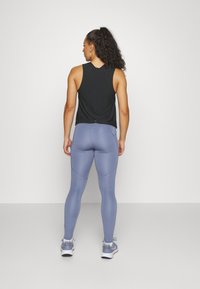 Črna brezrokavnik s svetlo modrimi leginsami. Leggins sta z gladko teksturo in subtilnimi perforacijami na straneh.