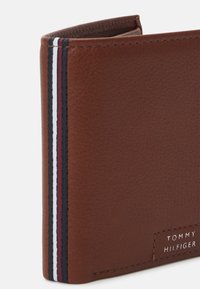 Brauner Leder Geldbeutel mit strukturiertem Finish, der ein vertikales Streifenmuster in Marineblau, Rot und Weiß aufweist. Logo in Silber geprägt.