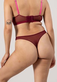 Bordeaux mesh bh en string set met roze banden, voorzien van een haak- en oogsluiting, dunne elastische afwerking en een doorzichtige textuur.