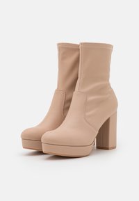 Beige tekokuituleather nilkkurit paksulla korolla, pyöreällä kärjellä ja sijoitetulla pehmusteella. Ominaisuuksiin kuuluu minimalistinen ompelu reunoilla.