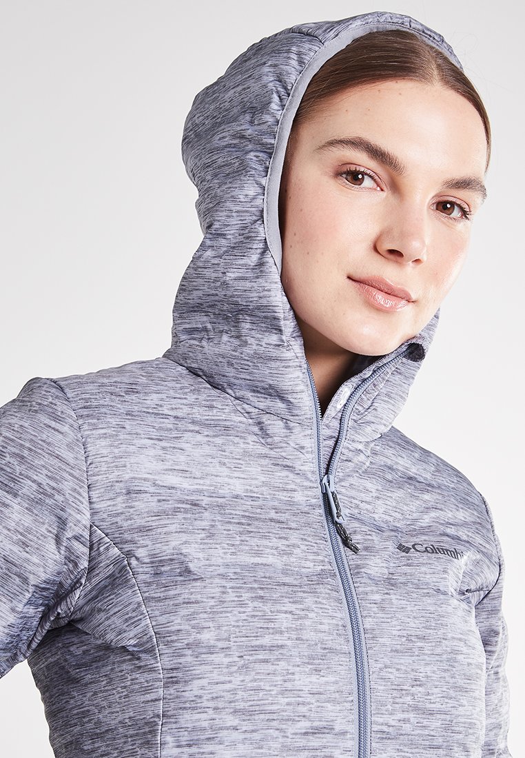 Chaqueta con capucha gris con un patrón texturizado, que cuenta con un cierre central con cremallera y el logo de Columbia en la parte superior izquierda.