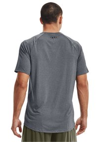 Šedé atletické tričko s krátkým rukávem, s texturovaným povrchem, raglánovými rukávy a logem Under Armour na zadní straně.