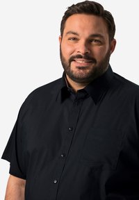 Svart kortärmad skjorta med nedklädd krage, en bröstficka och en mjuk yta. Knapparna är svarta med matt yta.